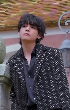 a young man standing next to a stone wall