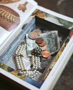 an open book with beads and coins in it on a table next to a dollar bill