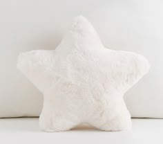 a white star pillow sitting on top of a bed next to a stuffed animal toy