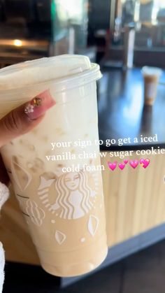 a person holding a cup with a drink in it and the caption reads, your sign to go get a iced vanilla chay sugar cookie