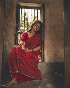 a woman in a red dress sitting on the ground next to a jail cell door