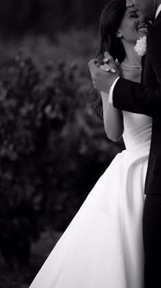 a bride and groom share a tender moment together in black and white photo by the bushes