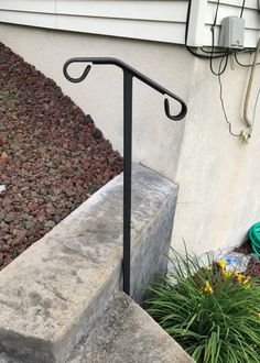 an iron hand rail on the side of a house next to some flowers and plants