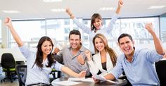 a group of people sitting at a table with their arms in the air and smiling