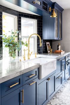 a kitchen with blue cabinets and gold faucets