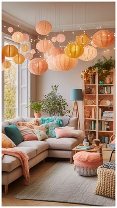 a living room filled with lots of furniture and hanging lanterns above the couches in front of a window