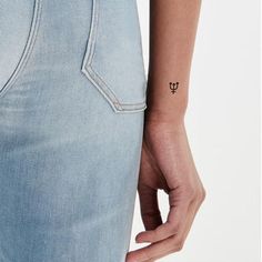 a woman with a small tattoo on her left arm is wearing light blue denims