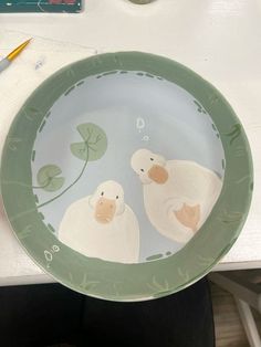 a plate with two ducks painted on the front and side, sitting on a table