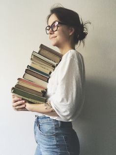 a woman holding a stack of books in her hands