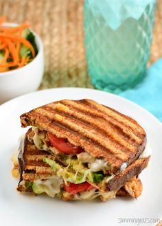 a grilled sandwich with lettuce, tomatoes and carrots on a white plate