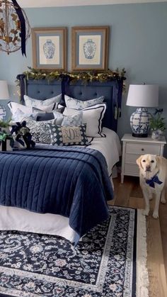 a bedroom decorated in blue and white with a dog standing next to the bed