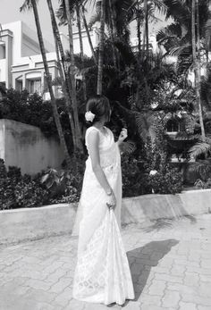 black and white photograph of woman in dress looking at palm trees