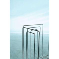 three metal racks sitting next to each other on top of a blue surface with water in the background