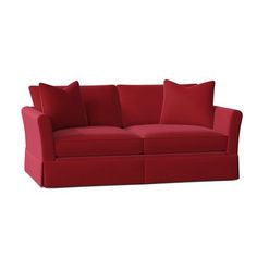 a red couch with two pillows on the back and one pillow on the side,