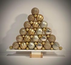 a christmas tree made out of gold and silver ornaments on top of a white shelf