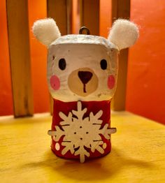 a teddy bear with a red sweater and white snowflake on it's head