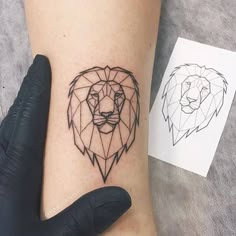 a small lion tattoo on the left arm and wrist, with an outline of a lion's head behind it