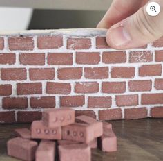 a person is placing bricks on top of a brick wall to make a house model