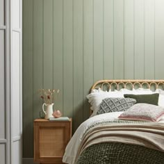 a bedroom with green walls and white bedding, along with a wicker headboard