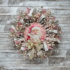 a wreath with a santa clause on it and some bows around the edges, hanging on a wooden wall