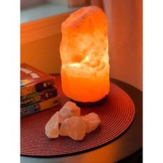 a himalayan salt lamp sitting on top of a table next to books and a book