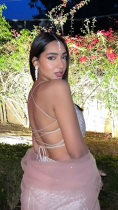 a woman in a pink dress posing for the camera with her back to the camera