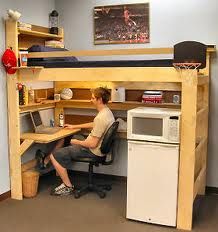 a man sitting at a desk in front of a computer on top of a wooden shelf