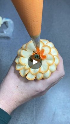 a person holding an orange and white flower shaped object