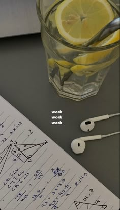 an apple, lemon and headphones sitting on top of a table next to a notebook