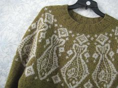 a green sweater with white designs on it