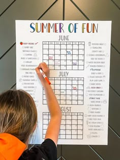 a young child writing on a summer of fun calendar