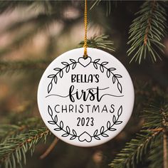 a personalized ornament hanging from a christmas tree with the name bella's first christmas