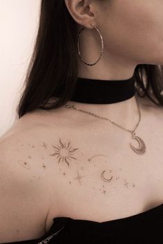 a woman with a tattoo on her chest is looking at the sky and stars that are flying in the air