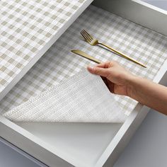 a person holding a fork and knife in a drawer with a checkered table cloth