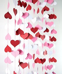 red and white paper hearts hanging from strings on a wall in the shape of hearts