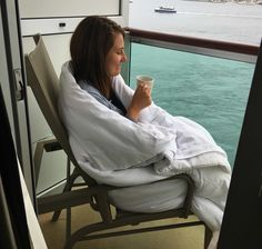 a woman sitting in a chair with a blanket on her head and holding a cup