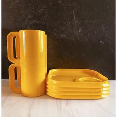 a stack of yellow mugs and plates on a table