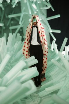 a man in a tuxedo and polka dot scarf walking through an art installation