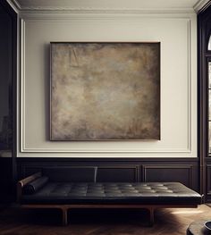 a painting hanging on the wall above a couch in a room with wood flooring