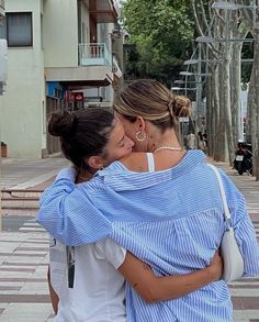 two women hugging each other on the street