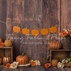 an arrangement of pumpkins and flowers are on display in front of a wooden wall