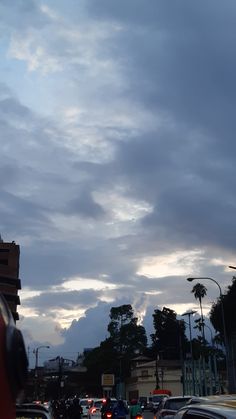 cars are driving down the street under cloudy skies