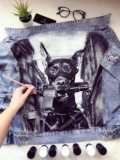 someone is painting a jean jacket with a dog on it