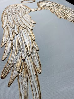 an angel wing is shown on the hood of a car with gold foiled wings