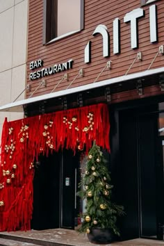 a christmas tree in front of a bar restaurant with decorations on the door and windows