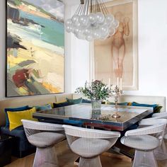 a dining room table with chairs and an art piece hanging on the wall above it