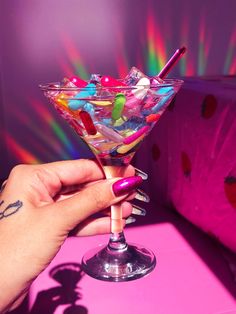 a woman's hand holding a martini glass filled with candy