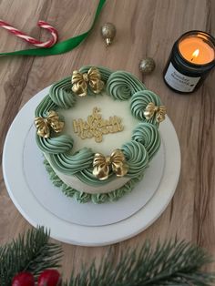 a green and white frosted cake sitting on top of a table next to a candle