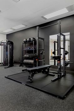 an empty gym with equipment in the middle and mirrors on the wall behind it,