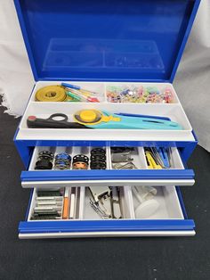 an open blue box with scissors and other crafting supplies